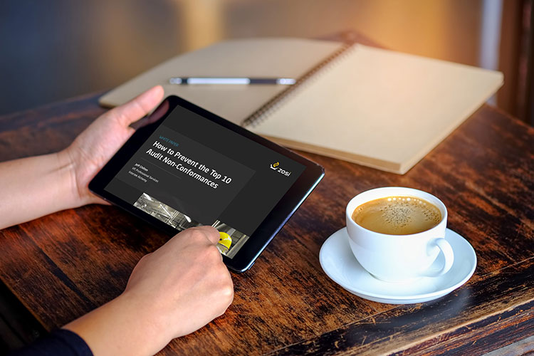 Worker at table with tablet, coffee, and notebook open